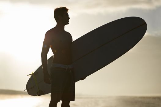 Chasing waves is his passion. A handsome young surfer at the beach craving a good wave.