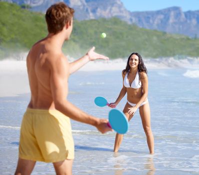 They are always active. A happy young couple playing tennis on the beach together together.