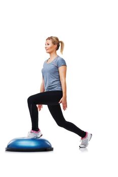 Shes focused on exercise. An attractive young woman doing lunges on a bosu-ball.