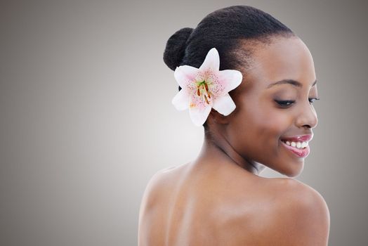 Soft as a petal. Studio portrait of a beautiful african american model with an orchid against a gray background.