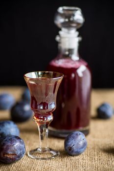 plum red wine in a glass and a decanter against the background of ripe large plums