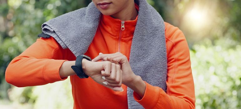 Woman fitness athlete check pulse with smartwatch while training for exercise in forest. Runner using gps tracker to monitor progress, heart rate and calories burned during workout or exercise.