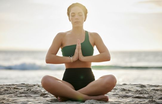 Woman, yoga and meditation on the beach in sunset for spiritual wellness, zen or workout in the outdoors. Female yogi relaxing and meditating for calm, peaceful mind or awareness by the ocean coast
