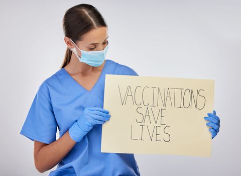 Help us save lives. a young female nurse holding vaccination signage against a studio background.