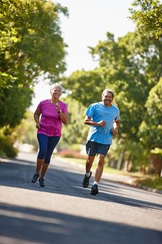 Loving a sunny day run. a mature couple jogging together on a sunny day.