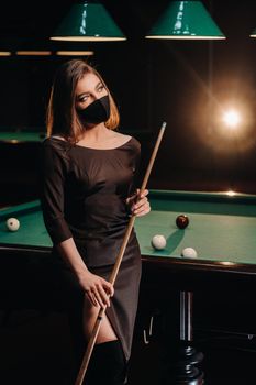 Masked girl in a pool club with a cue in her hands