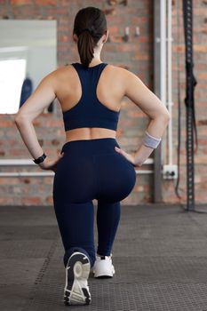Woman, stretching legs and workout in gym for health, self care and muscle development on floor. Girl, fitness and exercise with lunge, balance or healthy with focus, body goals and vision in Toronto