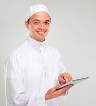 Islamic man, tablet and happy portrait for Muslim reading, education or culture standing in white background. Young person, smile and digital tech learning for religious mindset isolated in studio