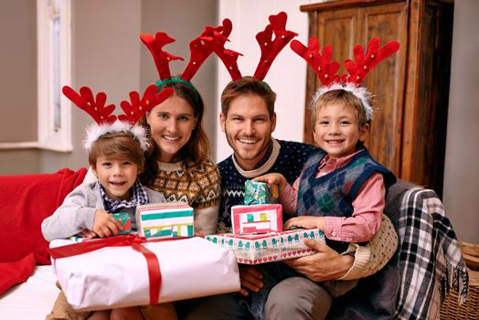 Christmas is a time for family. a family wearing reindeer antlers while enjoying themselves at Christmas.