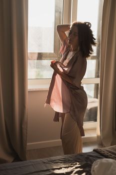 Young woman enjoying sunny morning on bedroom - wake-up and wellness concept