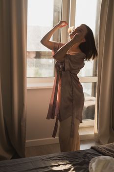 Young woman enjoying sunny morning on bedroom - wake-up and wellness concept