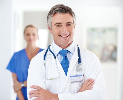 Healthcare with a smile. Portrait of a male doctor with a colleague standing in a the background