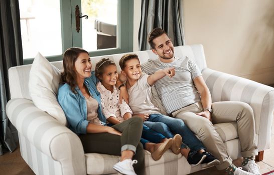 The love of family keeps us grounded. a happy young family relaxing on the sofa and watching tv together at home.