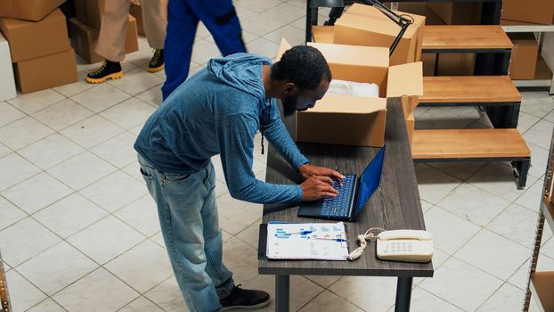 Young office employee arranging goods in packages