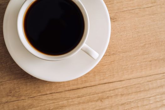Flat lay cup of black coffee with a saucer on a wooden table