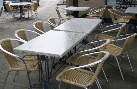 empty tables in an outdoor cafe in Antwerp wet seats and tables after a rain