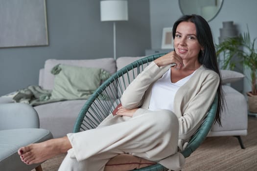 portrait of successful woman sitting on modern armchair at home
