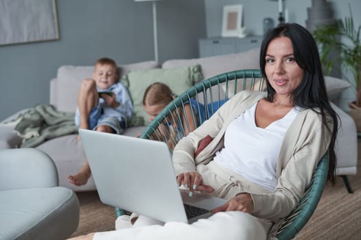 woman using laptop with interest at home while child relax on sofa