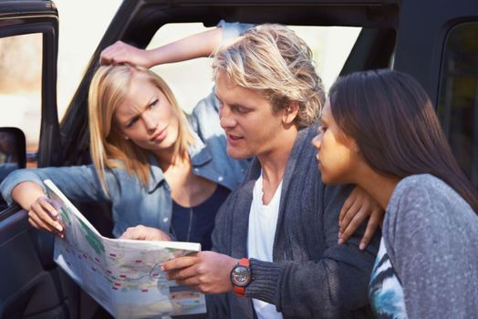 This is what happens when men dont ask for directions. Portrait of a group of friends leaning against their van, reading a map.