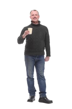 Confident handsome man in jeans holding cup with hot drink and smiling