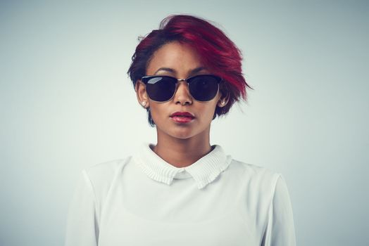 Beauty is an attitude. a beautiful young woman wearing sunglasses against a grey background.