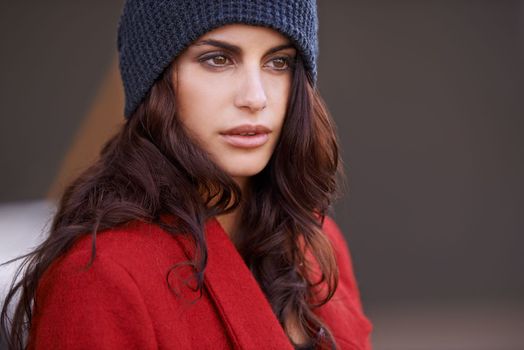 Scarlet stunner. a beautiful young woman wearing a red winter coat and a beanie.