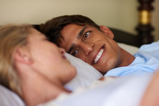 I love waking up next to you. a young married couple lying in bed while looking at each other.