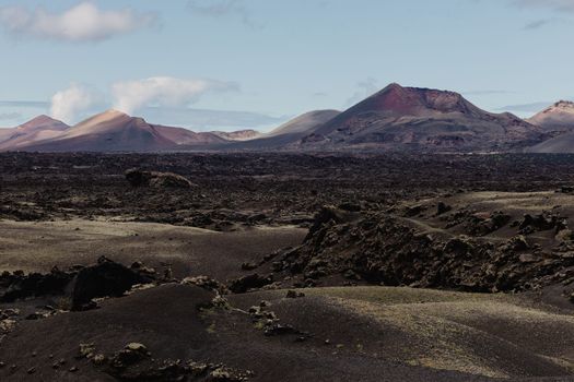 Black volcanic landscape of Timanfaya National Park in Lanzarote. Popular touristic attraction in Lanzarote island, Canary Islands, Spain.