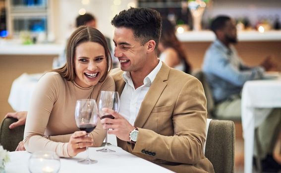 Love, wine and happy couple at a restaurant for valentines day, celebration and bonding while laughing. Alcohol, fine dining and woman with funny man on first date, anniversary or birthday dinner