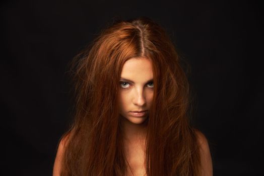 Giving you her crazy eyes. Portrait of a pretty redhead with messy hair.