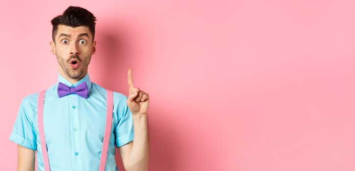 Creative man pitching an idea, saying suggestion with raised finger, standing on pink background
