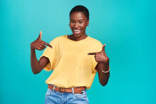 Say it like you mean it. Studio shot of a confident young woman pointing at her t shirt against a turquoise background.