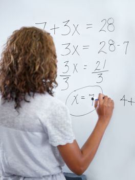 Maths class. A young teacher doing maths equations on the whiteboard.