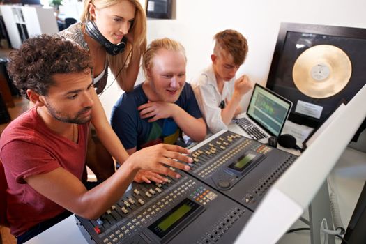 This song just needs some tweaking...Four young music producers working on a mixing desk.