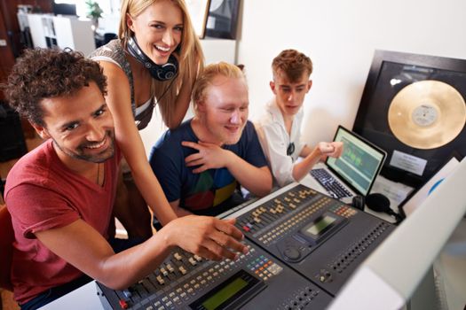 Creating a hit takes time...Four young audio engineers working on a mixing desk.