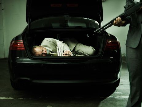 Staring at a barrel while stuffed in the boot. A bound and gagged businessman stuffed into the boot of a car as his assailant points a gun at him.