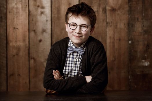 Cute and clever. Young boy in retro clothing wearing spectacles with a smile.