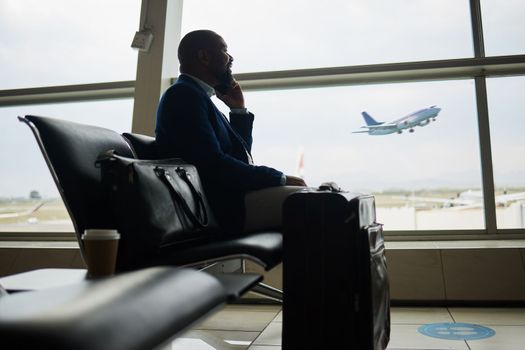 Black man, phone call and luggage at airport for business travel, trip or communication waiting for flight. African American male in conversation or discussion on smartphone ready to board airplane