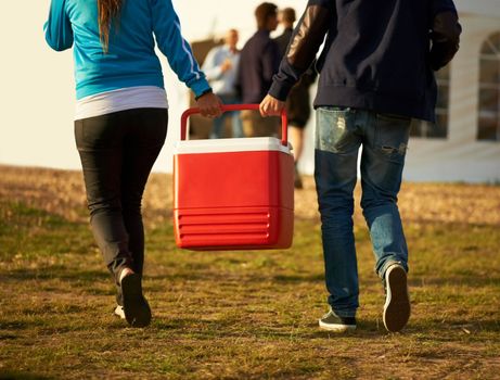 Keeping it cool. Rear view of two people carrying a cooler box down to the stage at a music festival