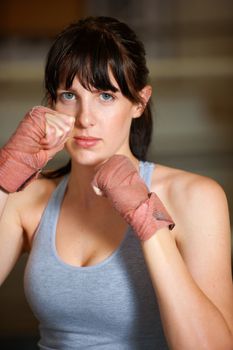 At the ready. Portrait of a determined female boxer standing ready to fight.