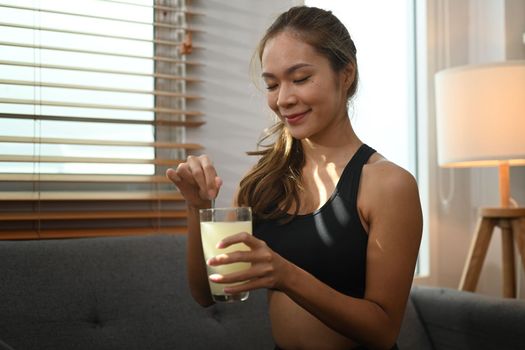 Attractive sporty woman drinking collagen supplements after exercise. Natural supplement for skin beauty and bone health