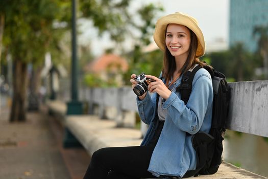 Caucasian woman tourist with camera sitting on bridge bench near river. Travel Lifestyle vacations concept