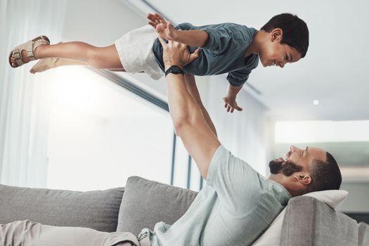 Relax, smile and lifting with father and son on sofa of living room for bonding, playful and support. Wellness, game and strong with dad and child in family home for care, quality time and happy