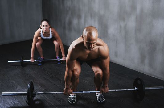 Stepping up their fitness routine. two people lifting barbells during a gym workout.