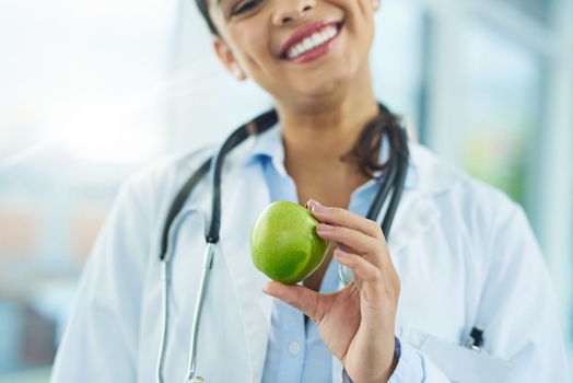These nutrients are vital for health and maintenance of your body. Portrait of a young female doctor holding an apple.