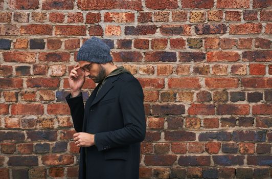 Casual winter wear. a handsome young man in trendy winter attire against a brick wall.