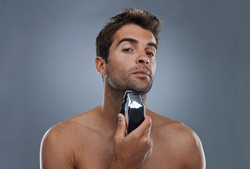 Grooming for the modern man. Studio portrait of a handsome young man shaving with an electric razor.