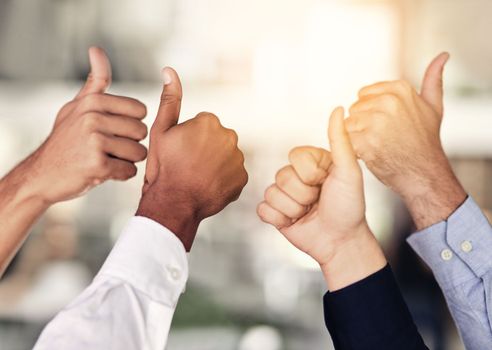 We couldnt agree more. Closeup shot of a group of unidentifiable businesspeople showing thumbs up in an office.
