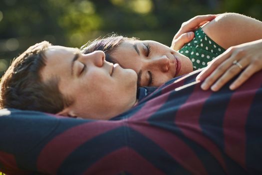 Keep love close to the heart. an affectionate young couple enjoying an afternoon nap in the park.
