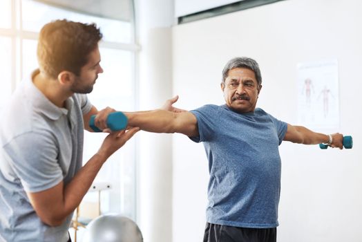 Youre doing great. a young male physiotherapist helping a mature male patient with movement exercises at a clinic.